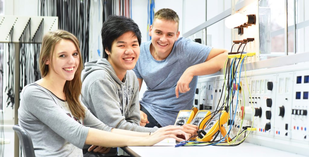 Three students collaborate on a project in an electronics lab.