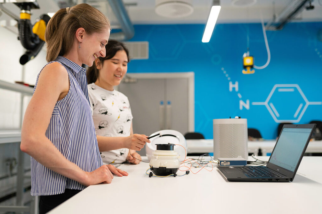 A teacher and student test an engineering project in the classroom.