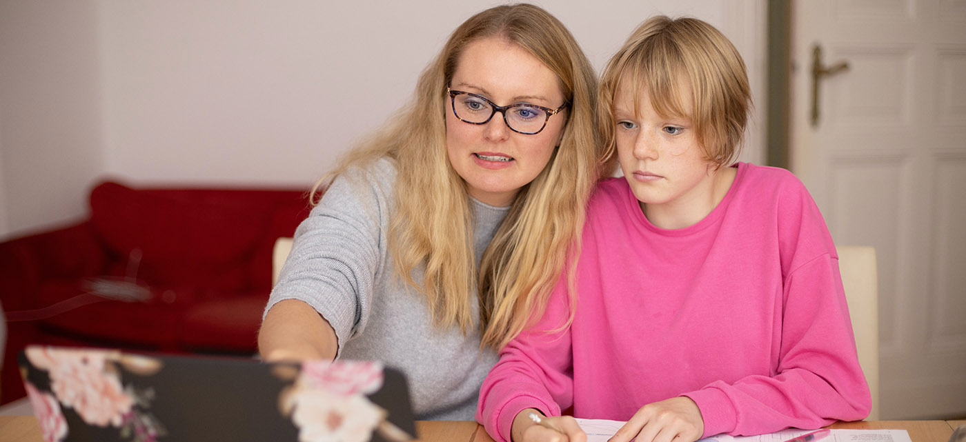 A mother and child work together on a laptop.