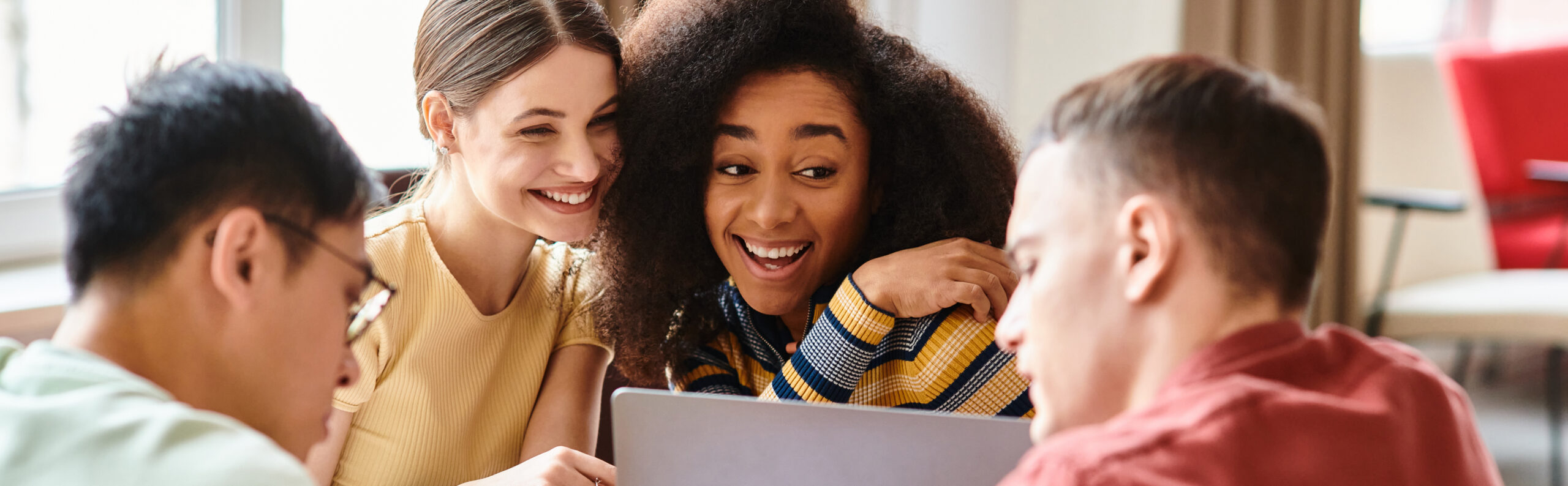 4 students sitting around a laptop 
